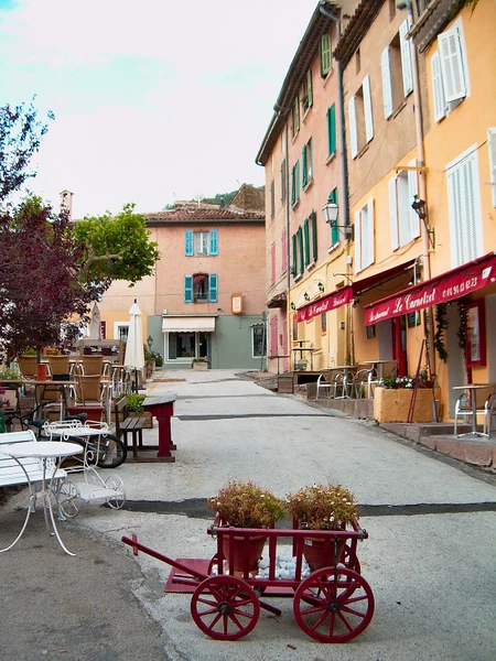 Photographie aérienne ou paysagère de La Garde-Freinet dans le Var, montrant le village provençal perché avec ses caractéristiques architecturales typiques (toitures rouges, ruelles pittoresques, bâtiments en pierre locale), le château et l'église au cœur du village, entourés de collines boisées couvertes de forêt méditerranéenne et de végétation. L'image doit être nette, professionnelle, prise en lumière naturelle de jour, sans texte ni logo visible, et clairement distinctive des vues côtières de Saint-Tropez et Sainte-Maxime, représentant l'arrière-pays varois où intervient l'entreprise d'électricité.